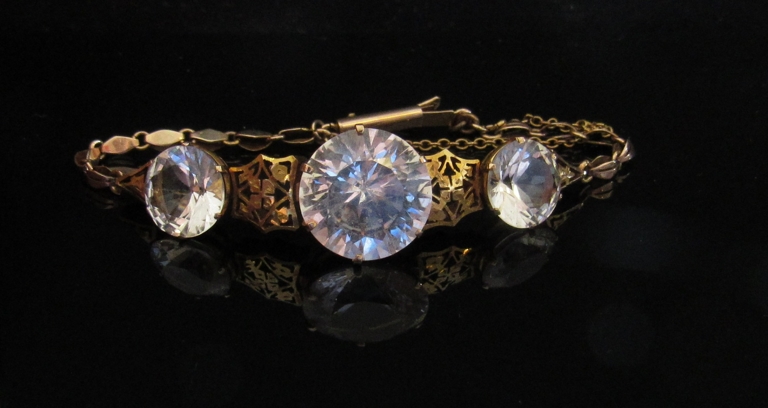 A gold bracelet set with three zircons linked by delicate foliate panels, unmarked, 10. - Image 2 of 2