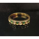 An 18ct gold diamond and emerald half hoop ring. Size P, 3.