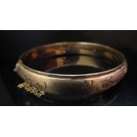 A 9ct gold stiff hinge bangle, engraved decoration, 5.5cm diameter, 15.