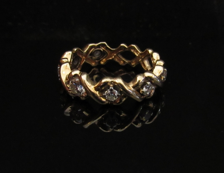 A gold eternity ring with seven diamonds set in open X settings, stamped 14k. Size M, 4.