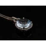 A cushion cut circular aquamarine pendant framed by diamonds in a white gold mount stamped 750 with