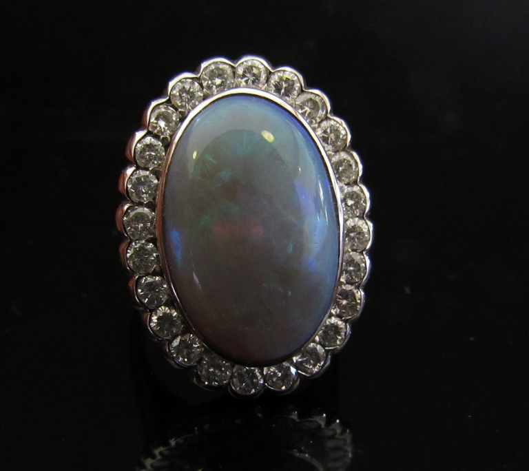 An opal and diamond ring the large oval opal 20mm x 13mm framed by diamonds, stamped 18ct.