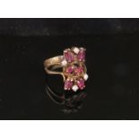 A gold diamond and ruby cluster ring in split shoulders, stamped 10k. Size O, 3.