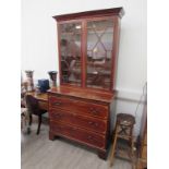 A Georgian mahogany glazed two door bookcase cabinet above a three drawer base with brushing slide,