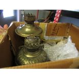 A box containing brass and metal items including oil lamps,
