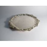 A plated salver with foliate border on scroll feet,