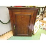 A George III country oak wall hanging corner cupboard with single door and key