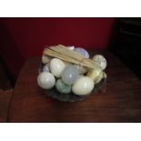 A silver plate basket containing assorted stone eggs and fan
