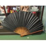 A paper and wooden fan of large proportions