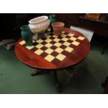 A reproduction mahogany circular games table with chequered insert top and quatreform base to brass