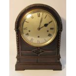 A late 19th/early 20th Century carved oak bracket clock of arched form with twisted supports,