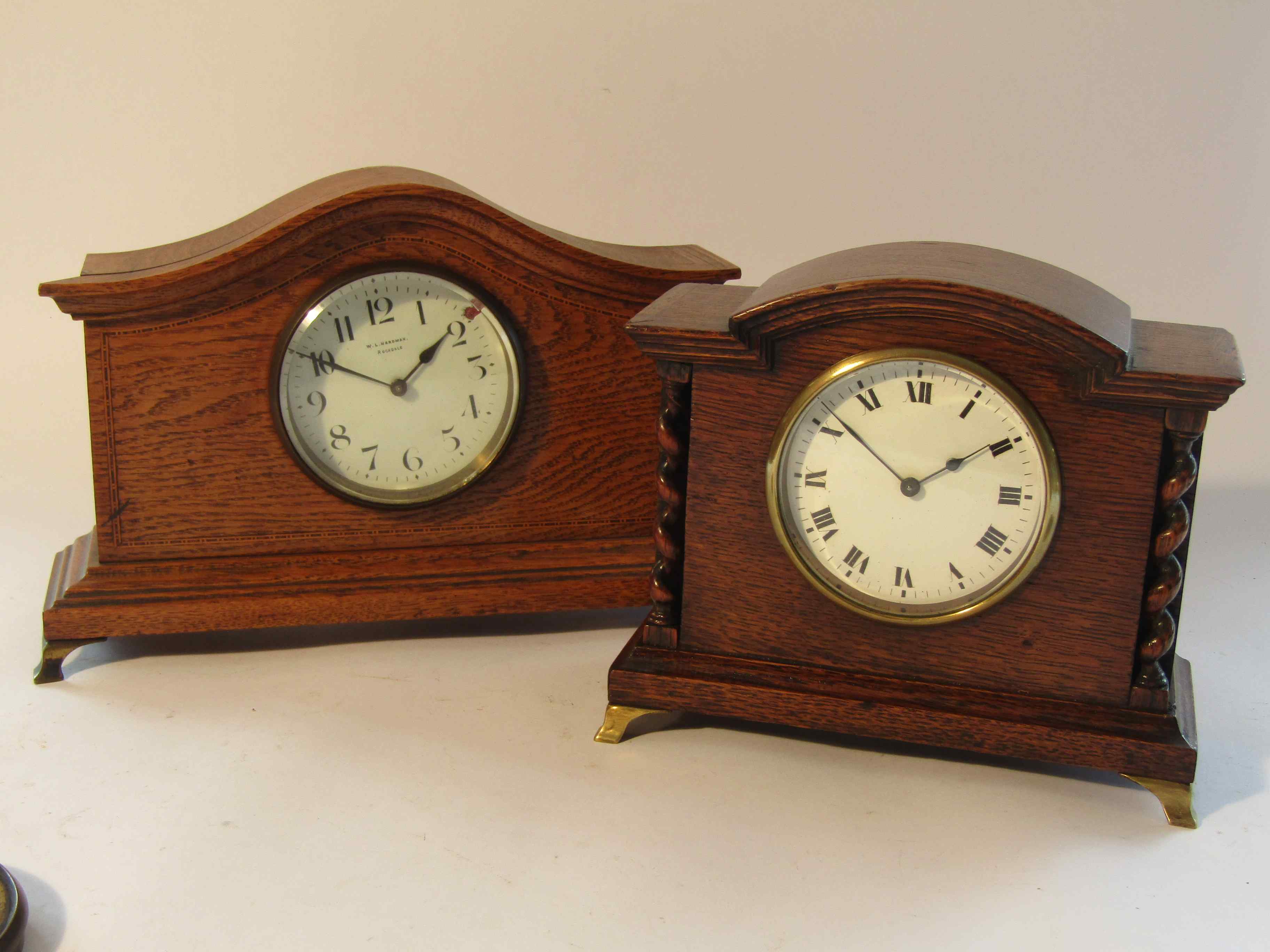 Two Edwardian oak timepieces of architectural form with enamelled Arabis and Roman dials,