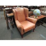 A leather wingback chair on cabriole legs
