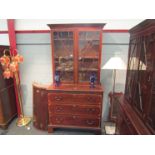 A Georgian mahogany glazed two door bookcase cabinet above a three drawer base with brushing slide,