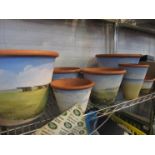 Nine modern hand painted terracotta pots of various sizes,