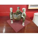 A Dux style table centrepiece of three figures holding aloft a conch shell,