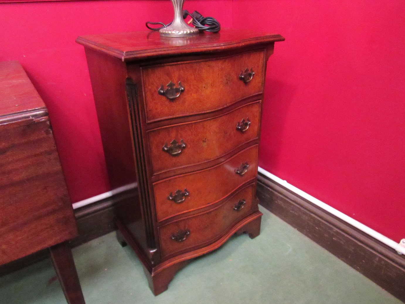 A Georgian style crossbanded burr walnut serpentine front four drawer chest of small proportions,