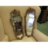 A pair of modern cherub-top cartouche shaped wall mirrors in gilded frames,