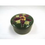 A Moorcroft lidded trinket pot of cylindrical form, floral design, green glazed,