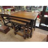 An oak nest of three graduating occasional tables on baluster turned legs joined by stretchers,