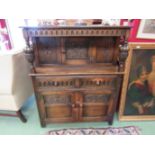 An oak hall cupboard, two cupboard top to two drawer, two cupboard base, heavily carved supports,