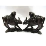 A pair of wooden carved boys on water buffalo with wire inlay,