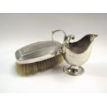 A silver cream jug and silver backed hairbrush,