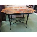A lacquered coffee table with wavy rim and ebonised base on outswept legs,