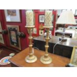 A pair of gilt acanthus leaf candlesticks with ornate candles,