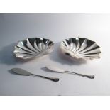 A pair of Atkin Brothers silver scallop form dishes with associated butter knives, Sheffield 1908,