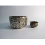 A 19th Century Burmese silver bowl with all over embossed detail, 10cm diameter and similar salt,