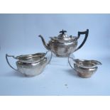 A silver Carrington & Co three piece tea set with ebony knop and handle, misshapen base,