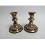 A pair of silver squat form candle sticks, dented, 12cm tall,