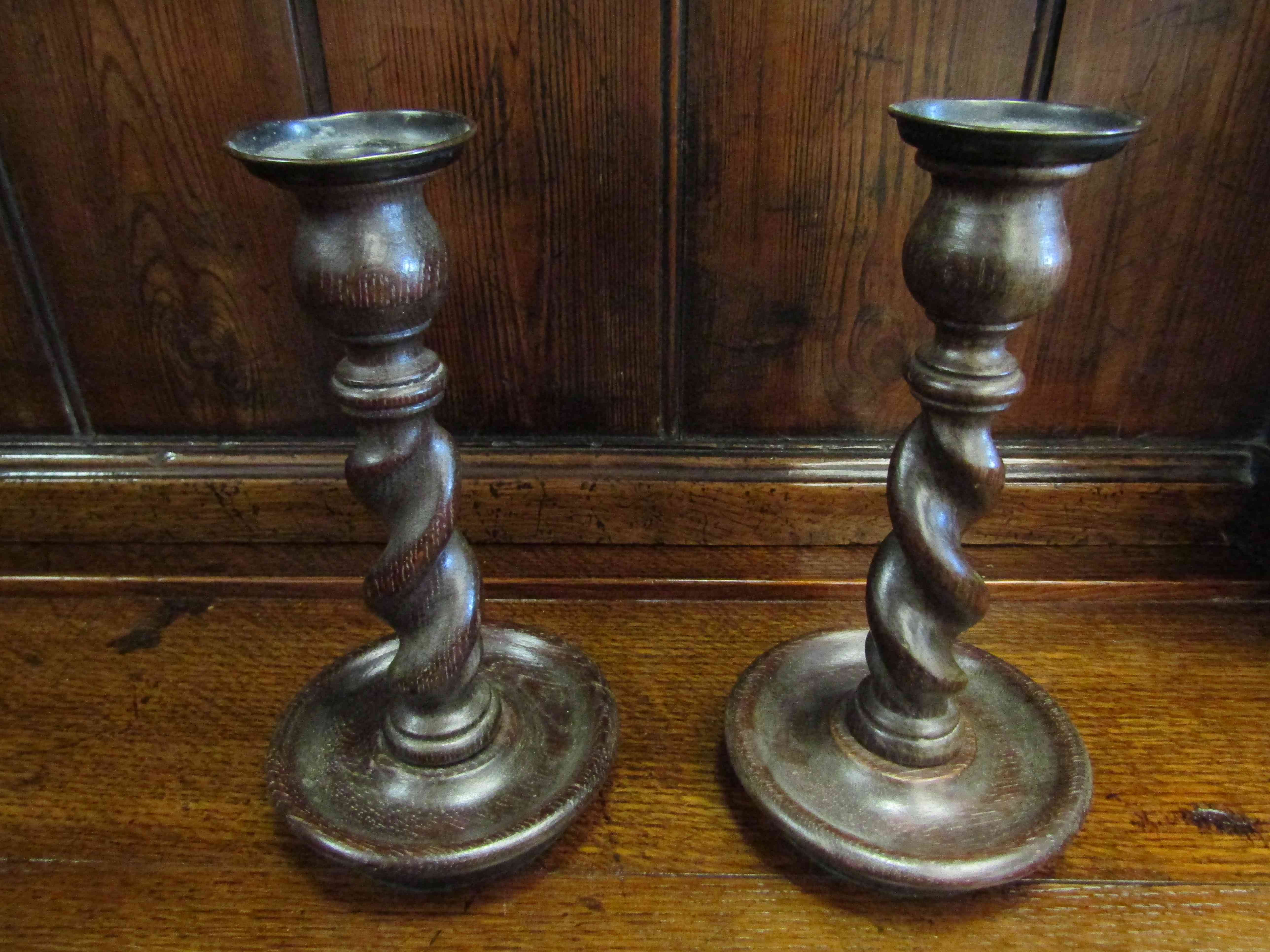 A pair of oak barley twist candlesticks with drip trays,