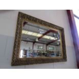 An ornately gilt framed bevel edged wall mirror,