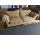 An upholstered swag design three seater sofa with covers on brass capped feet and castors,