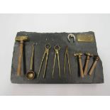 A miniature set of blacksmith's tools on a slate plinth