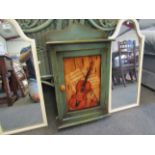 A rustic painted wall hanging cabinet with violin design, gallery back and shelved interior,