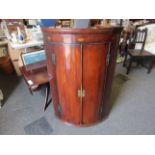 A George III mahogany bow-front wall-hanging corner cupboard with shell patere inlay,