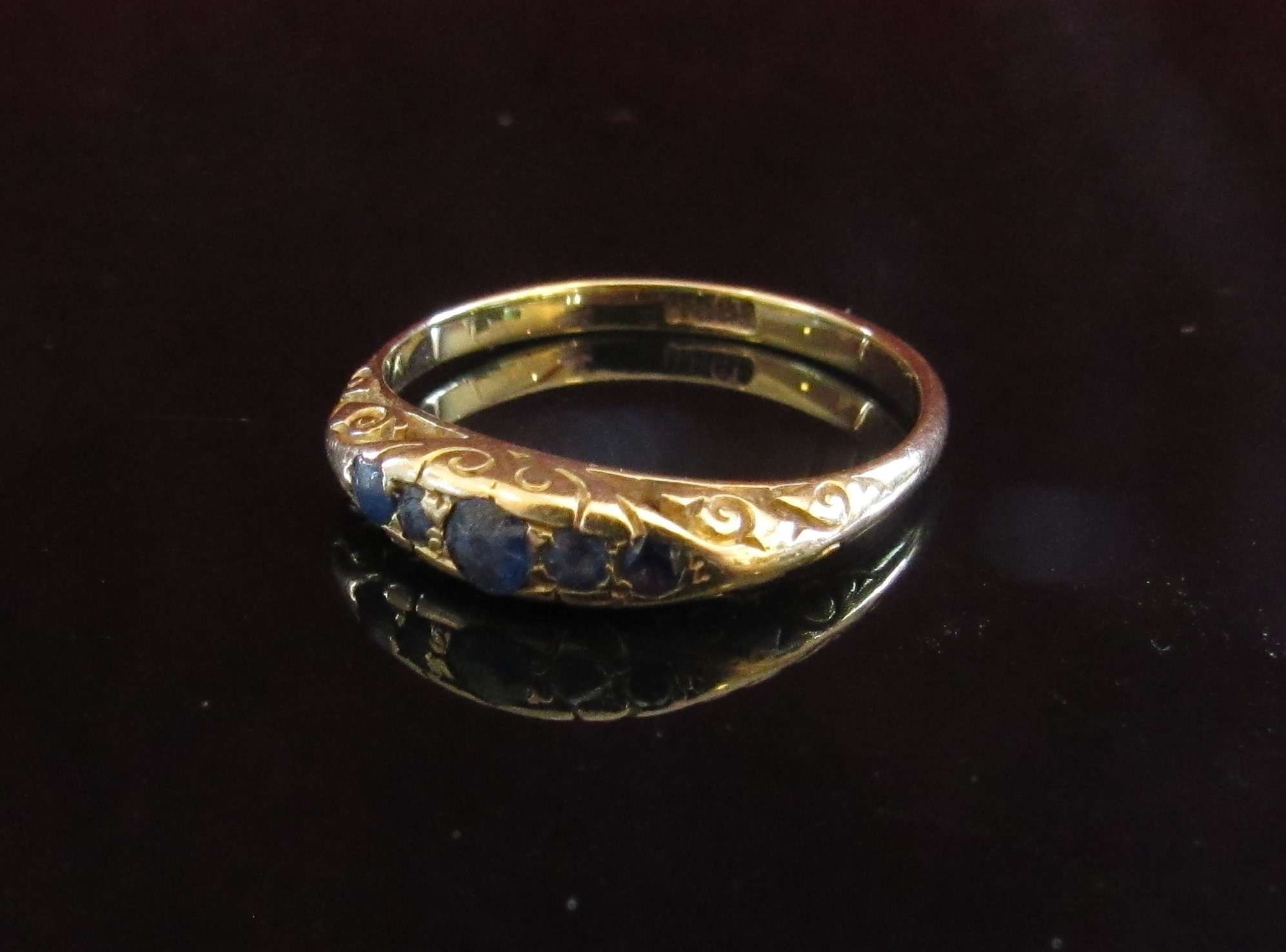 A gold ring set with five sapphires in rubover setting. Size O, 2.