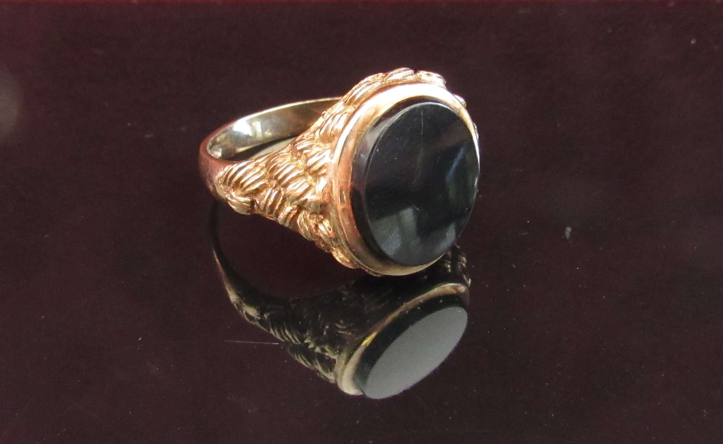 A 9ct gold onyx signet ring with textured shoulders. Size S/T, 5.