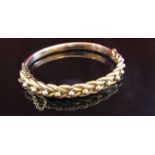 A gold stiff hinge bracelet with engraved link and ball design, stamped 9ct, some small dents, 9.