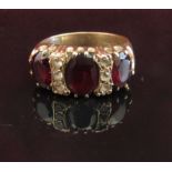 A 9ct gold three stone garnet ring, the central garnet flanked by three clear stones.