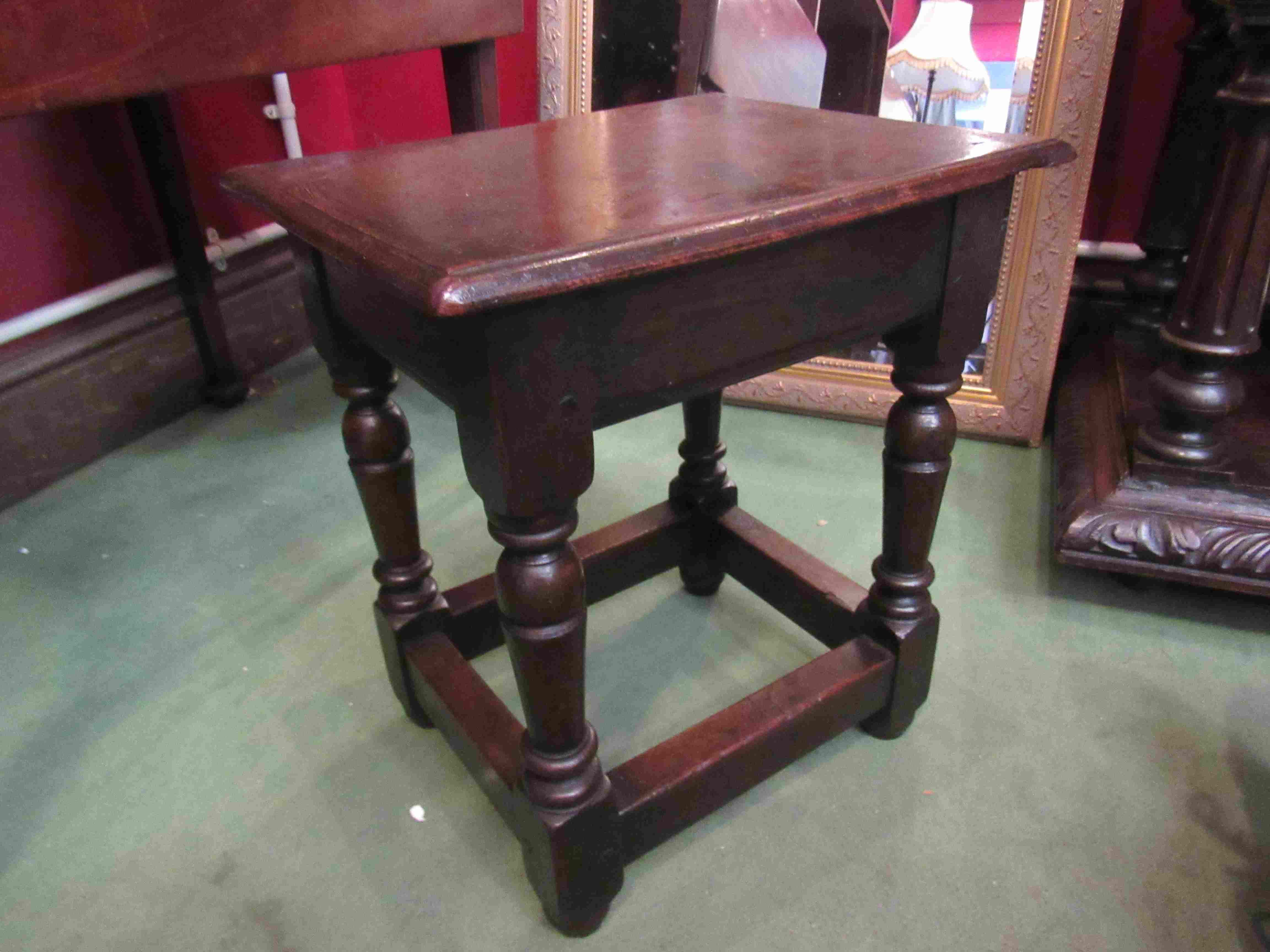 An 18th Century oak stool on turned legs joined by stretchers,