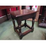 An 18th Century oak stool on turned legs joined by stretchers,