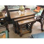 An oak nest of three graduating occasional tables on baluster turned legs joined by stretchers,