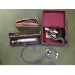 A box of vintage medical equipment including stethoscope and blood pressure monitor etc