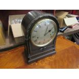 A late 19th/early 20th Century carved oak bracket clock of arched form with twisted supports,
