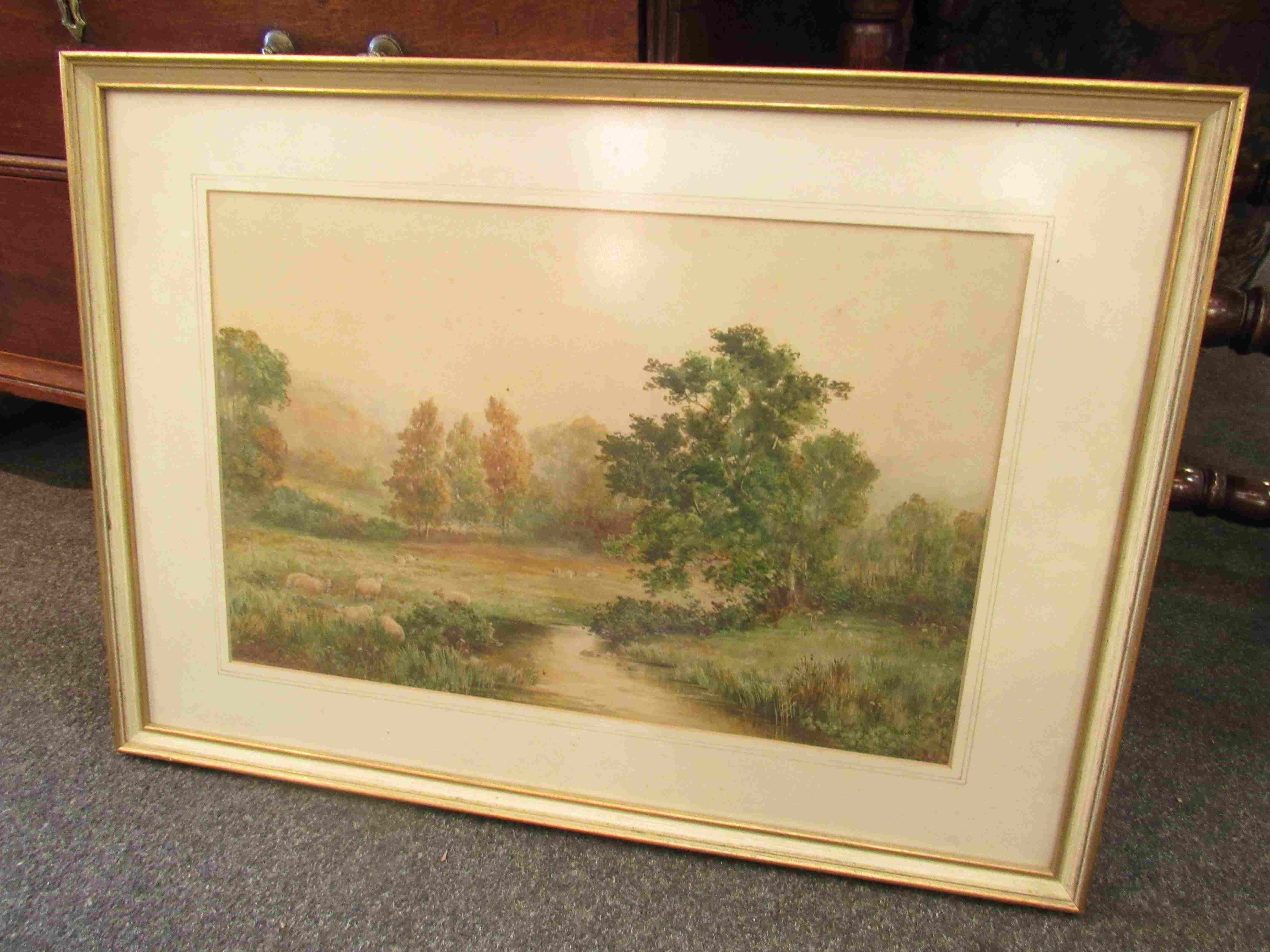 W.W. HODGES (XIX) A framed and glazed watercolour of sheep in a river valley pasture.