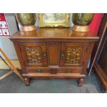 A modern carved oak low cupboard with carved panel doors and two drawers,